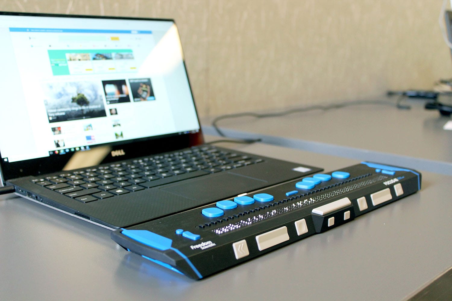 Laptop mit einer angeschlossenen Braillezeile davor.
